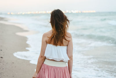 Rear view of woman standing at beach