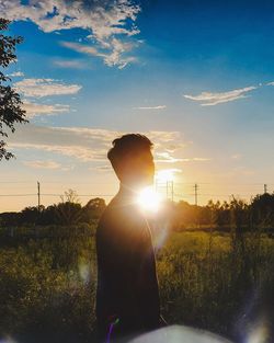 Man standing on field against sky during sunset