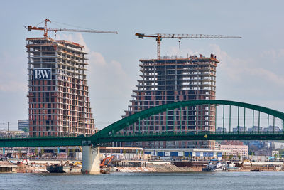 Crane by building against sky