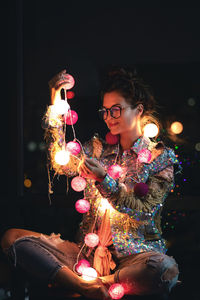 Rear view of woman holding christmas tree at night