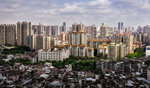 Aerial view of buildings against cloudy sky in city