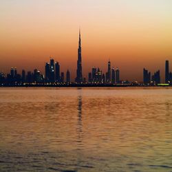 Sea with cityscape in background at sunset