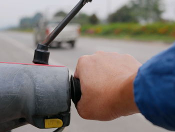 Cropped hand of man motor scooter on road