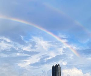 Low angle view of rainbow over buildings against sky