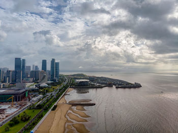 Aerial view of city buildings against cloudy sky