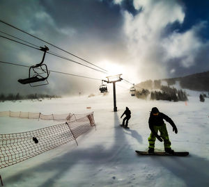 People walking on snow covered mountain against sky