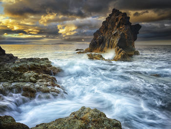 Rock formations in sea against cloudy sky at madeira