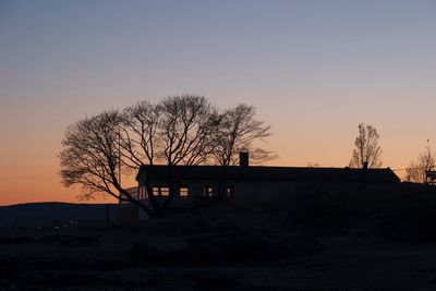 Silhouette built structure on field against sky during sunset