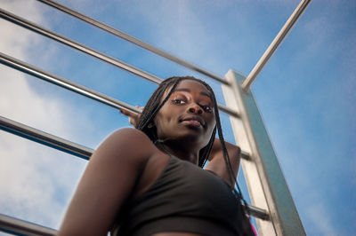 Low angle portrait of young woman looking away against sky