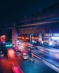 Light trails on road in city against sky at night