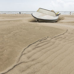 Deck chairs on sand at beach against sky