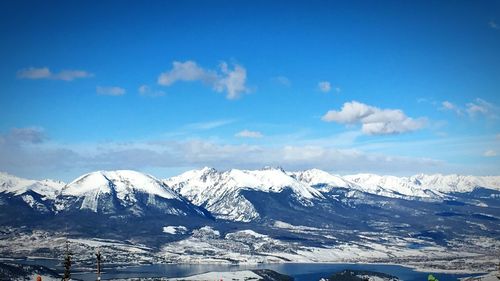 Scenic view of snow covered mountains against blue sky