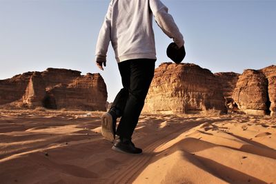 Low section of man on rock against sky