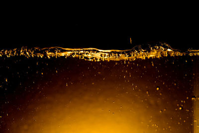 Water drops on illuminated city against sky at night