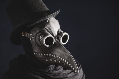 Close-up of person wearing mask against black background