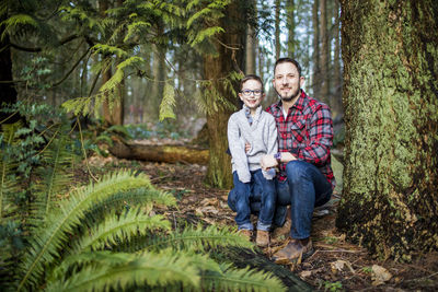 Father holds his handsome son in the forest.