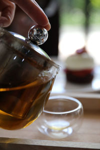 Close-up of hand pouring tea in cup on table