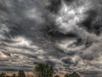 Low angle view of trees against cloudy sky