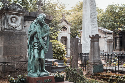 Statue in cemetery against temple