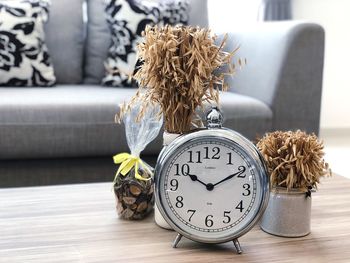 Close-up of alarm clock and potted plants on table at home