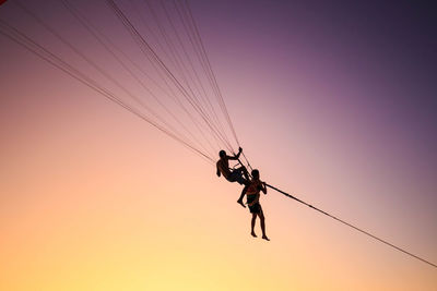 Low angle view of man parasailing against sky during sunset