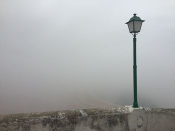 Illuminated street light against sky during winter