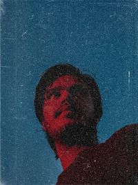 Close-up portrait of man against blue sky