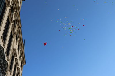 Low angle view of balloons flying against clear blue sky