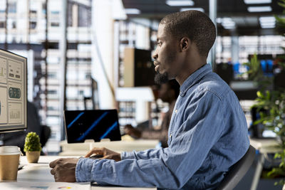 Rear view of man using mobile phone in office