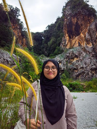 Portrait of young woman standing against mountain