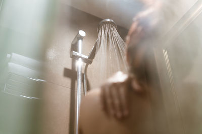 Rear view of woman bathing in shower 