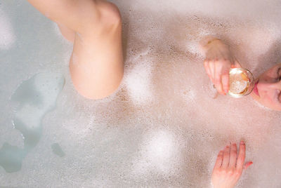 High angle view of woman having drink while relaxing in bathtub