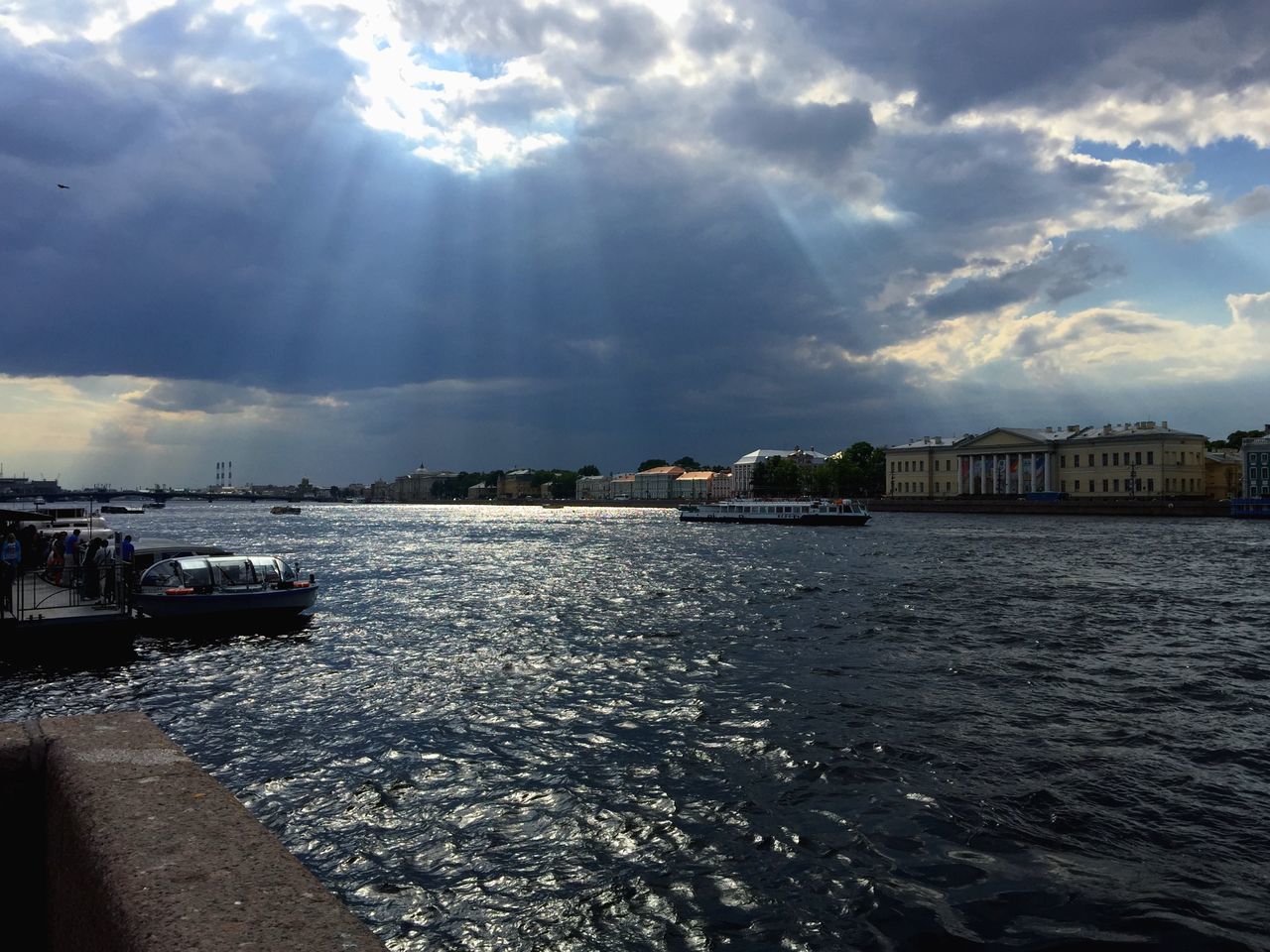 water, building exterior, architecture, built structure, waterfront, sky, sea, cloud - sky, rippled, nautical vessel, city, cloud, sunlight, transportation, river, cloudy, boat, nature, residential structure, sunbeam