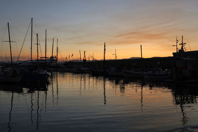 Sailboats moored at harbor during sunset