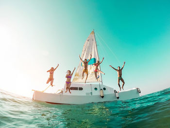 People on jumping in sea from yacht against clear sky