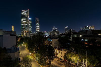 Illuminated buildings in city against sky at night