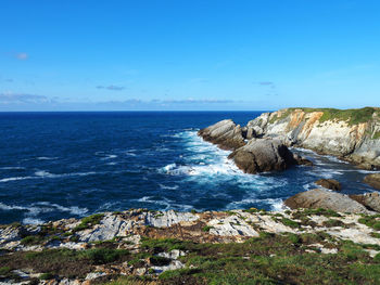 Scenic view of sea and rocks against clear blue sky
