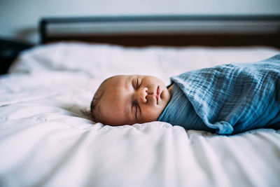 Close up of newborn sleeping on bed alone