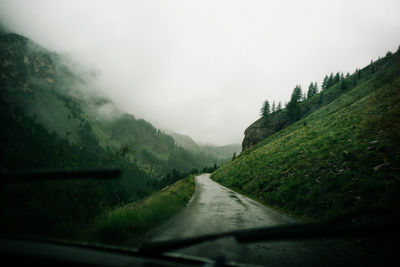 Road amidst trees seen through car windshield