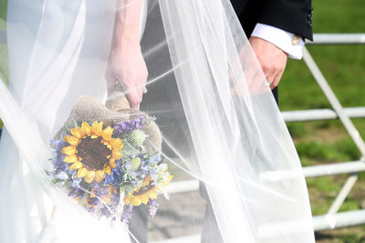 Midsection of bride and bridegroom standing outdoors