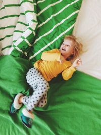 High angle view of smiling girl lying on bed