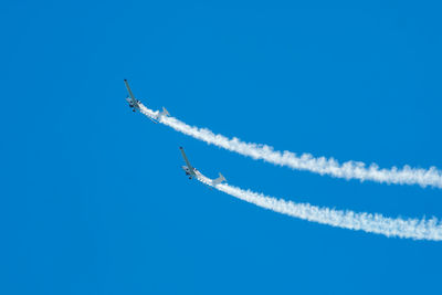Low angle view of airplane flying against clear blue sky