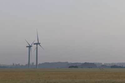 Wind turbines on field against clear sky