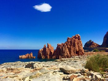 Rock formations by sea against clear blue sky