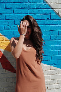 Portrait of happy young woman standing against wall