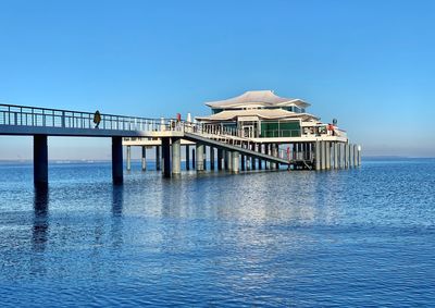 View of pier over sea against clear blue sky