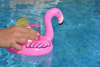  hand holding a cold drink in a pink flamingo floating drinks holder