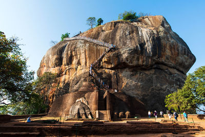 People walking on rock against sky