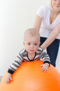 Portrait of cute baby boy holding toy against white background