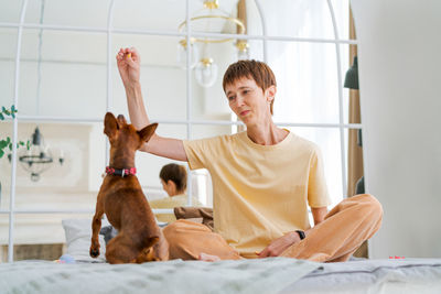 Owner playing with joyful dog at home, happy mature woman enjoying exercise